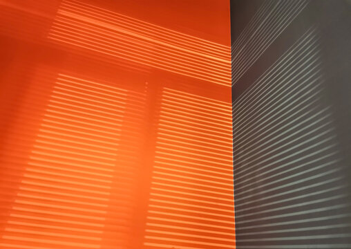 Shadow from the blinds. The walls are painted orange and gray. Light and shadow from the window. Shadow overlay effect backgrounds. Reflected shadow on wall.