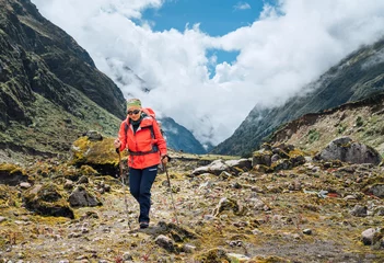 Papier Peint photo autocollant Makalu Woman in sunglasses with backpack and trekking poles dressed red softshell jacket hiking during Makalu Barun National Park trek in Nepal. Mountain hiking, traveling and active people concept image.
