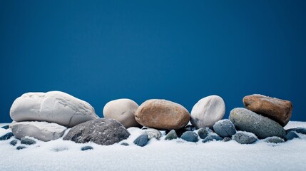 Stones in the snow on a blue background with space for text