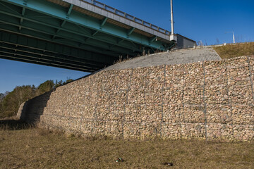 engineering structure made of stones behind metal wire netting to strengthen the river bank near...