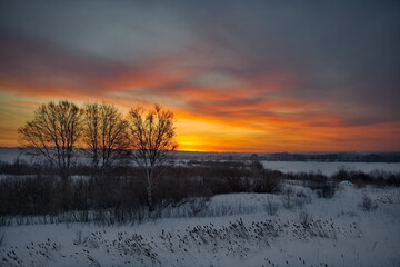 Fototapeta na wymiar Russia, Southern Kuzbass. Colorful picturesque sunrise on a frosty morning in snow-covered fields.