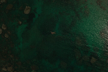 Aerial top nature view above green turquoise Adriatic sea in Albania. young woman swimming alone