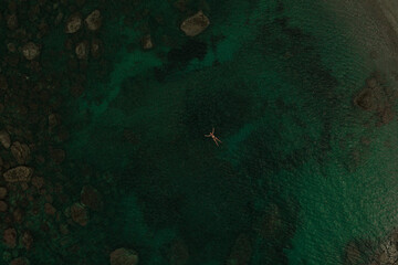 Aerial top nature view above green turquoise Adriatic sea in Albania. young woman swimming alone