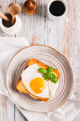 French croque madame hot breakfast sandwich on a plate on the table top and vertical view