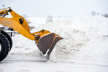A snowplow removes snow with a bucket