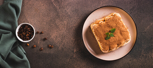 Tiramisu cake made of cookies, delicate cream and coffee on a plate top view web banner
