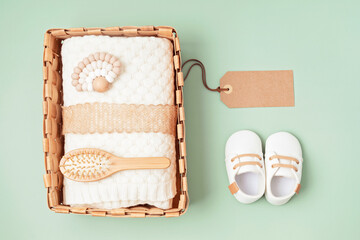 Top view of a wicker basket containing soft knitted blankets and natural wooden baby grooming...