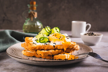 Toasts with cream cheese, cucumber, poached egg and sesame seeds on a plate on the table