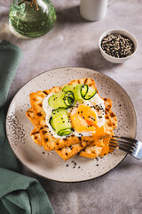 Waffles with poached egg, cucumber and sour cream on a plate on the table vertical view