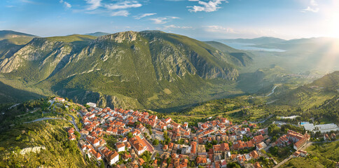 Aerial, panoramic view of Delphi village and surrounding hills, visible ancient road from harbour to temple, colorful evening light. UNESCO World Heritage Site. Delphi, Greece.