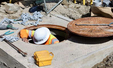 maintenance worker using the manhole to check underground equipment