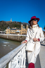 Stylish woman with maroon hat and white coat on Paseo de la Concha