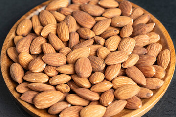 Fresh natural healthy almonds nuts on a wooden plate.