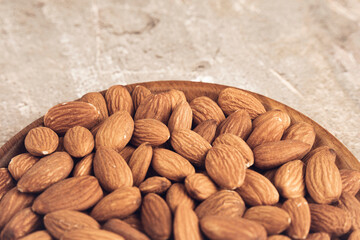 Fresh natural healthy almonds nuts on a wooden plate.