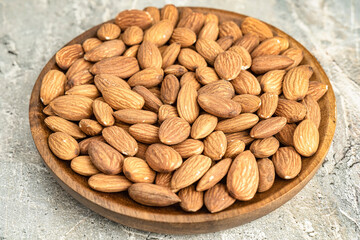 Fresh natural healthy almonds nuts on a wooden plate.