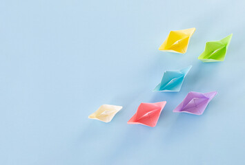 color paper boats on blue background