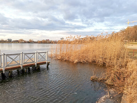 Autumn landscape. View of the lake, a wooden bridge on the water and reeds growing along the shore