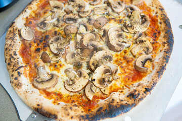 Photograph Chopped shot of a part of the pizza on an oven paddle. pizza, mushrooms, cheese, tomato