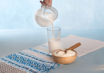 Powdered milk and whole milk in a jug on a light blue background