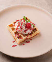 Viennese waffles with berry sauce and cream on a light background