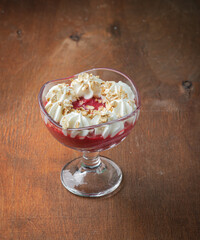 Berry dessert with whipped cream in glass glasses on a wooden background