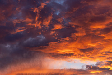 Fototapeta na wymiar Dramatic fiery cloudy evening sky at sunset, clouds of bright colors in twilight