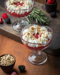 Berry dessert with whipped cream in glass glasses on a wooden background