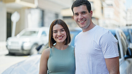 Fototapeta premium Beautiful couple hugging each other standing by car at street