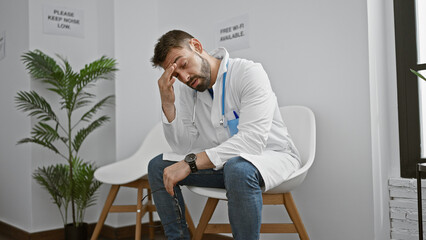 Overworked young hispanic man, a stressed doctor in uniform sitting solemnly on a chair in the...