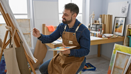 Happy young hispanic man drawing with confidence, art studioâ€™s resident artist at work