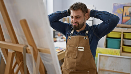 Relaxed young hispanic man, a portrait of handsome bearded artist, focused and concentrating on...