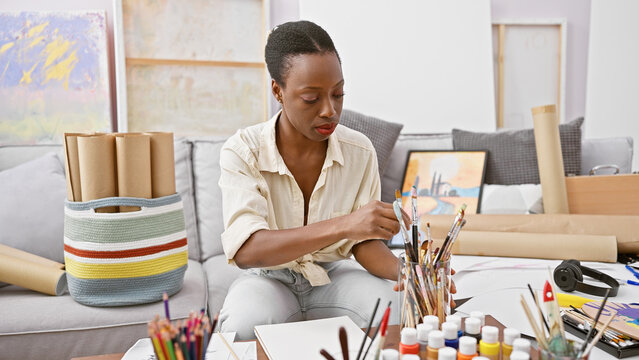 Beautiful african american woman artist immersed in drawing on her notebook at art studio