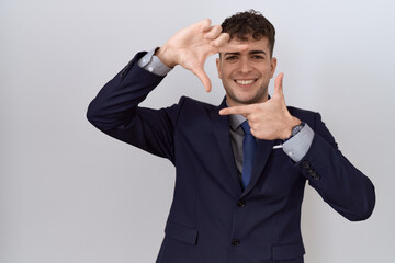 Young hispanic business man wearing suit and tie smiling making frame with hands and fingers with happy face. creativity and photography concept.