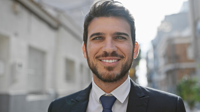 Portrait of a smiling hispanic man with a beard in a suit on a sunny urban street.