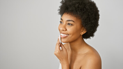 A smiling african american woman with curly hair poses against a white background in a beauty...
