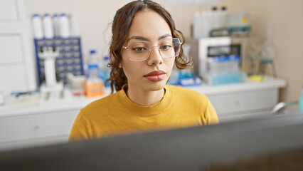 Focused woman wearing glasses analyzing data in a modern laboratory setting.