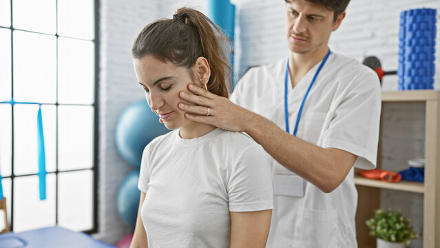 A male physiotherapist assesses a woman's neck in a modern physiotherapy clinic.