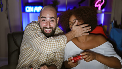 Two laughing gamers, man and woman, confidently streaming their game playing, video filling the room with digital entertainment. joyful couple using joystick, sharing a smile at their gaming room.