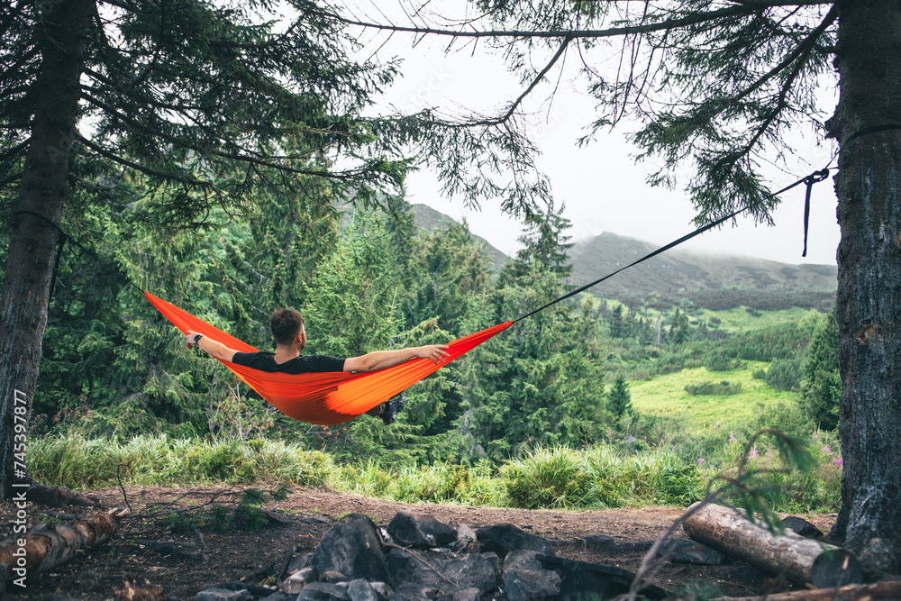 Poster man in hammock at camping site mountains on background