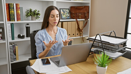Attractive young hispanic woman worker nails the business game, calling shots via video call at the...