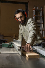 Vertical photo focused carpenter at table saw in workshop. Business concept.
