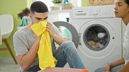Beautiful couple, engrossed in love and housework, smelling freshly washed clothes in their cozy...