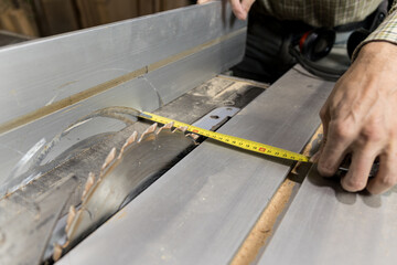 Horizontal photo meticulous carpenter measuring on table saw. Business concept.