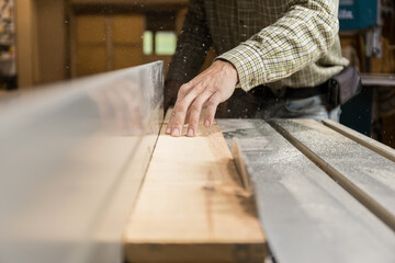 Horizontal photo artisan guiding lumber through saw. Business concept.