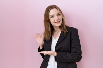 Young caucasian business woman wearing black jacket inviting to enter smiling natural with open hand