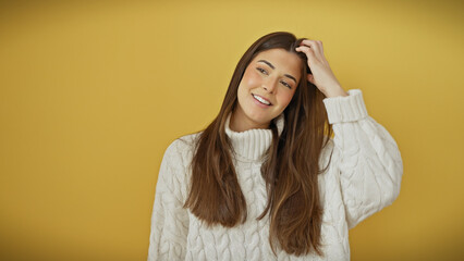 Young hispanic woman in a white sweater smiling against a yellow background.