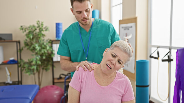 A woman receiving physiotherapy for her neck pain from a male therapist in an indoor rehabilitation clinic.