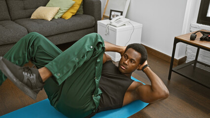 African american man exercising indoors on a blue mat in a modern living room.