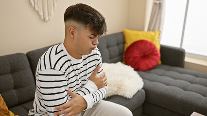Freezing winter blues, young hispanic man sits in the cold comfort of home, battling flu on the...
