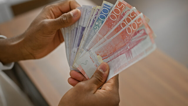 African man counting swedish krona indoors,